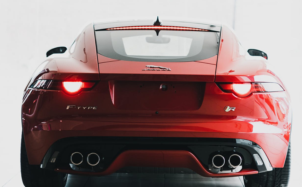 A red car with two exhaust pipes on the back.